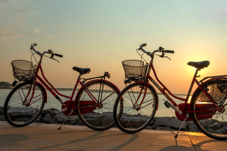 due biciclette rosse al tramonto sulla passeggiata lungo il mare di Caorle