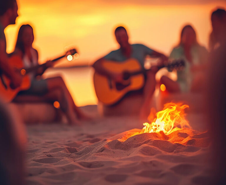 Ragazzi in riva al mare intorno al falò che suonano la chitarra al tramonto